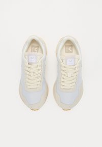 Sneaker azzurro chiaro e crema con tomaia in tessuto testurizzato, dettagli in suede, lacci beige e suola in gomma con un motivo circolare.