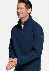 Marine blauwe zip-up pullover van textuurstof, met lange mouwen, een staande kraag en een klein merkteken op de linkermouw.