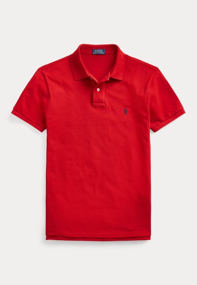 Punane lühikeste varrukatega polosärk krae, nööbiliistu ja väikese tumeda logoga vasakul rinnal, valgel taustal esitatud.
