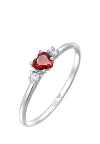 Silver ring med en hjärtformad röd ädelsten, flankeras av två klara stenar. Har polerat metal och delikata pronginställningar. Märkt 925.