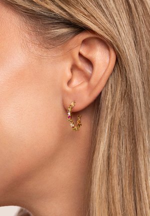 Goldene Creolenohrringe mit mehrfarbigen Edelsteinen, geschwungenem Design, strukturierten Oberflächen und einem sicheren Verschluss, die in einem Ohr getragen werden.