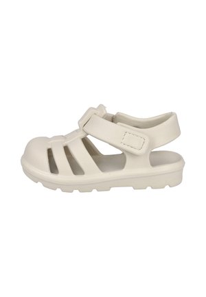 Sandalia beige de punta cerrada con tres tiras frontales, correa ajustable en el tobillo y suela gruesa diseñada para uso casual.