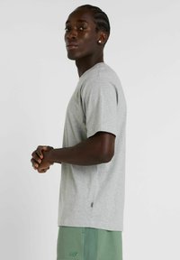 Grå kortærmet T-shirt med rund hals, lavet af blødt materiale, prydet med et minimalistisk design og en afslappet pasform.