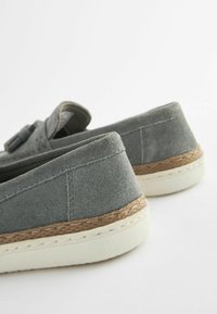 Szare zamszowe buty wsuwane o teksturowanym wykończeniu i plecionym śródstopiu z jutowego materiału. Posiadają białą gumową podeszwę oraz starannie wykończone szwy wzdłuż krawędzi.