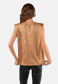 Ærmeløs brun top med teksturerede blomster mønstre, let tætsiddende form, glat stof og en bred udskæring. Vist fra bagsiden.