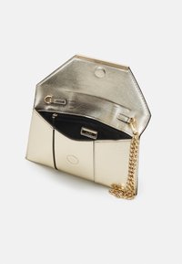 Borsa a pochette metallica dorata con tracolla a catena, texture liscia, forma esagonale e interno nero dotato di tasca con zip e slot per carte.