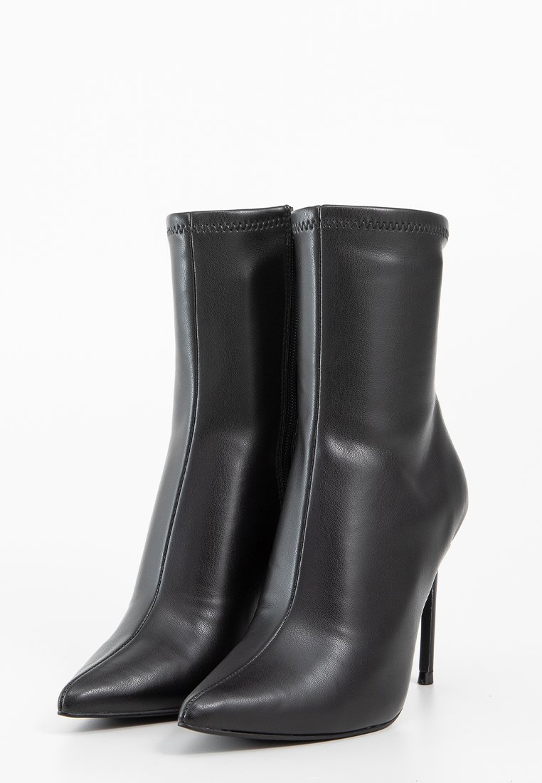 Czarne skórzane botki za kostkę z wydłużonymi noskami i wysokimi obcasami w kształcie stiletto. Gładka tekstura i minimalne szwy, zaprojektowane z elegancką sylwetką.