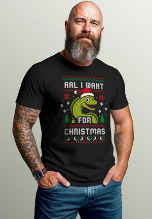 Schwarzes T-Shirt mit einem bunten Motiv eines Cartoon-Alligators, der einen Weihnachtsmannhut trägt, zusammen mit festlichem Text und weihnachtlichen Dekorationen.