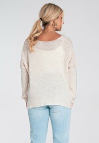 Lekki, kremowy sweter o luźnym kroju, z raglanowymi rękawami i szerokim dekoltem. Teksturowana tkanina oraz ribbowe wykończenie u dołu.