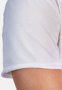 Vit bomullströja med en slät textur, featuring rund hals och korta ärmar. Sömmen är sydd med en dubbel söm för ökad hållbarhet.