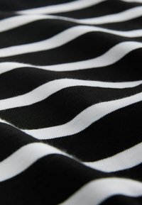 Črno-bela tkanina z vzorcem črt, ki ima gladko teksturo, z izmenjujočimi se valovitimi vzorci. Črte so različnih širin.