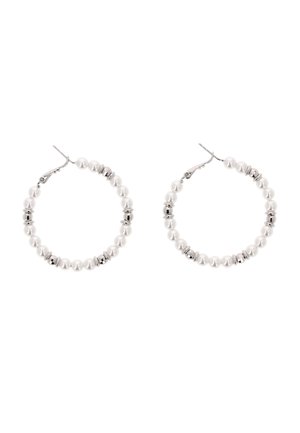Hoop-øreringe lavet af hvide perler og sølvperler med låse lukninger på en hvid baggrund.