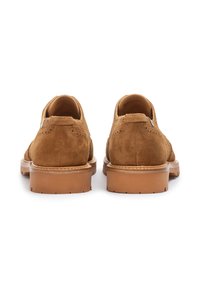 Zapatos de ante marrón con detalles de brogue, tacón redondeado y suela de goma color beige. La vista trasera muestra un cordón corto y un acabado limpio.