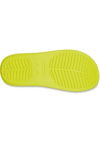 Semelle en caoutchouc jaune vif avec un motif de bande de roulement texturé et des rainures pour l'adhérence. Marquée "crocs" et taille "W 7."