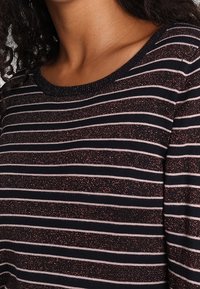 Bluzka w paski z długim rękawem, ozdobiona granatowymi i jasnoróżowymi paskami z subtelnym połyskiem. Miękka tkanina z klasycznym okrągłym dekoltem.