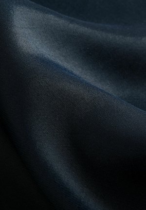 Ciemnoniebieska tkanina o gładkiej fakturze, lekko połyskująca, z tkanym wzorem, ukazująca miękkie fałdy i krzywizny.