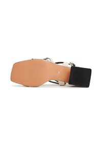 Sandale à talon beige avec un bloc de talon en caoutchouc noir carré, une fine sangle de cheville et une semelle beige lisse, légèrement texturée. Taille 39 visible.