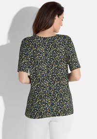 Korte mouwen top met een zwarte achtergrond en een meerkleurig gespikkeld patroon in blauw, geel en wit. Ronde halslijn, zachte stof.