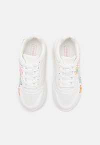 Weiße Sneaker aus perforiertem Material, mit bunten bestickten Blumenmotiven und flachen weißen Schnürsenkeln. Rosa Markenetikett innen.
