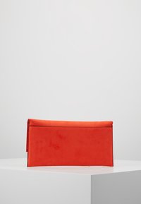 Kabelka z červeného sametu s elegantním obdélníkovým tvarem a plochým uzávěrem. Hladký povrch, minimalistický design, žádné viditelné kování ani vzory.