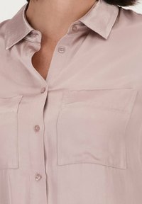 Lichtroze, kortemouw button-up shirt met een gladde, satijnen textuur. Beschikt over een klassieke kraag en twee voorzakken.