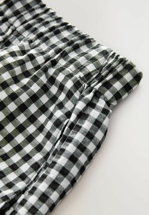 Czarnobiała tkanina w kratkę typu gingham z elastycznym paskiem, charakteryzująca się marszczoną fakturą. Wzór składa się z małych kwadratów ułożonych symetrycznie.