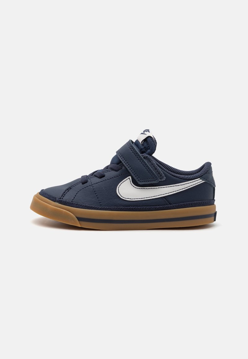 Baskets bleu marine avec un dessus texturé, design de swoosh blanc, sangle réglable et semelle en caoutchouc naturel. Présente des lacets pour un soutien supplémentaire.