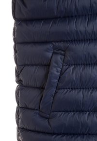 Granatowa kamizelka puchowa z poziomym pikowaniem, z boczną kieszenią i gładkim, błyszczącym stoffem. Lekka i ocieplana konstrukcja.