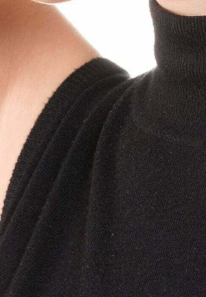 Gros plan sur une personne portant un pull noir à col roulé en maille, avec la peau visible au niveau du cou et de l'épaule.