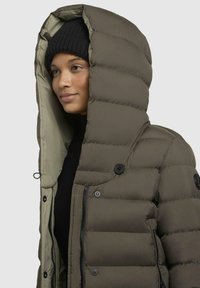 Padded olive green jacket with a large, lined hood, front zipper, and black buttons. Features a smooth texture and structured design.