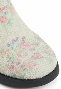 Botki do kostki w kwiatowy wzór z teksturowaną, off-white cholewką i czarną, płaską podeszwą. Wzór charakteryzuje się delikatnymi różowymi i zielonymi odcieniami.