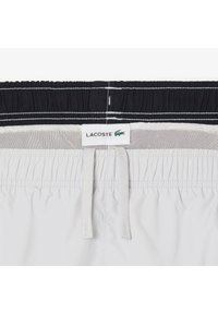 Lacoste zwemshorts met een zwart-wit elastische tailleband met trekkoord, textuur mesh voering en subtiele logo label.