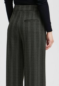 Grijze wijde broek met een subtiele verticale streep, voorzien van een achterzak en een gestructureerde stof voor extra visuele interesse.