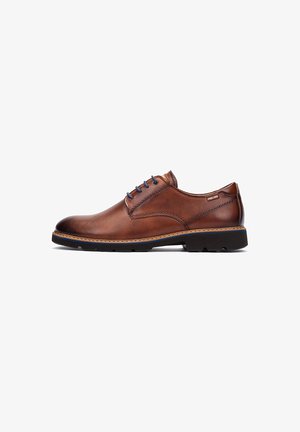 Chaussure en cuir marron à lacets, avec un embout arrondi, œillets bleus, détails cousus et une semelle en caoutchouc noir texturé.
