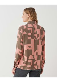 Camicia a maniche lunghe con un motivo astratto marrone e rosa, colletto e polsini con bottoni. Tessuto morbido con una vestibilità rilassata.