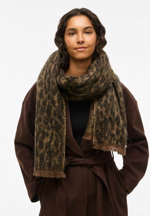 Brown leopard print scarf made of soft, textured fabric. Fringed edges complement the cozy drape around the model's neck.