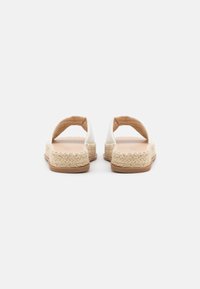 Sandales espadrilles blanches avec dos ouvert, semelle intermédiaire en jute tressé et semelle extérieure en caoutchouc. Texture douce et design minimaliste.