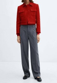 Cropped red textured jacket with two front pockets, paired with gray wide-leg trousers and black flats.