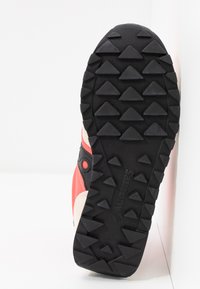 Schwarze Gummisohle mit dreieckigen Profilen, oberer Teil in Hellrosa und Koralle, verstärkte Ferse und Logo-Details an der Seite.