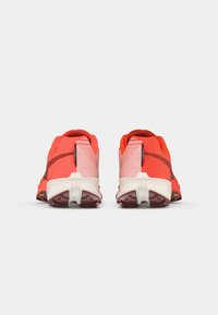 Røde atletiske sko med en struktureret mesh-overdel, kontrasterende sort stribe og en hvid mellemsål med en robust ydersål for godt greb.