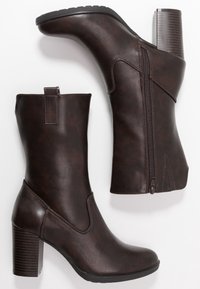 Botas de tobillo de imitación cuero marrón con tacón de apilamiento, cremallera lateral y lengüeta; textura suave con un sutil detalle de costura.