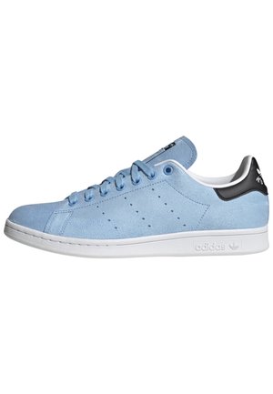 Baskets basses en daim bleu clair avec semelle blanche, lacets bleus, bandes latérales perforées et languette de talon noire avec logo blanc.