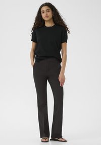 Black short-sleeve top paired with slim black trousers. The outfit features a simple design, smooth texture, and a relaxed fit.