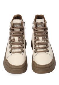 Beżowe skórzane sneakersy typu high-top z brązowymi akcentami. Posiadają sznurowaną konstrukcję, boczne zamki błyskawiczne oraz teksturowaną podeszwę zapewniającą przyczepność. Miękka podszewka wewnętrzna.
