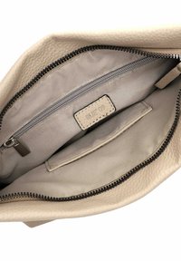 Beige leather bag interior with a zippered pocket and a slip pocket, featuring a textured surface and a label reading "RUE 09."