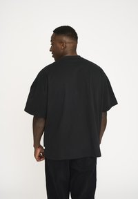 Sort oversized t-shirt i blødt stof med rund halsudskæring og korte ærmer. Har en afslappet pasform og forlænget bagkant for ekstra komfort.