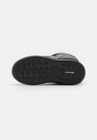 Sort sneakersål med tekstureret grebmønster; gummimateriale og forstærket hæl. Inkluderer logo detaljer på siden, flade snørebånd integreret.