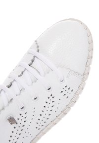 Baskets blanches en cuir avec un design perforé, des bords festonnés et des lacets blancs. Bout rond avec une semelle texturée et des accents gris subtils.