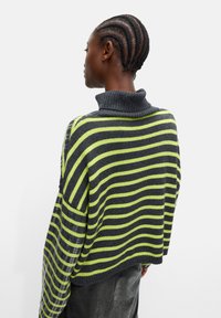 Oversized sweter typu golf w szaro-limonkowe paski, z teksturowanym splotem i szerokimi rękawami, o skróconej długości.