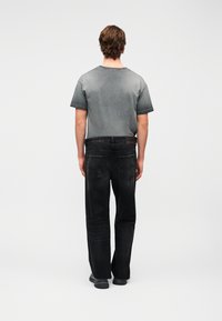 Γκρι μπλουζάκι με σταδιακή απόχρωση και κοντά μανίκια, συνδυασμένο με μαύρο τζιν με τσέπες πίσω και ετικέτα. Λεία υφή, casual εφαρμογή.